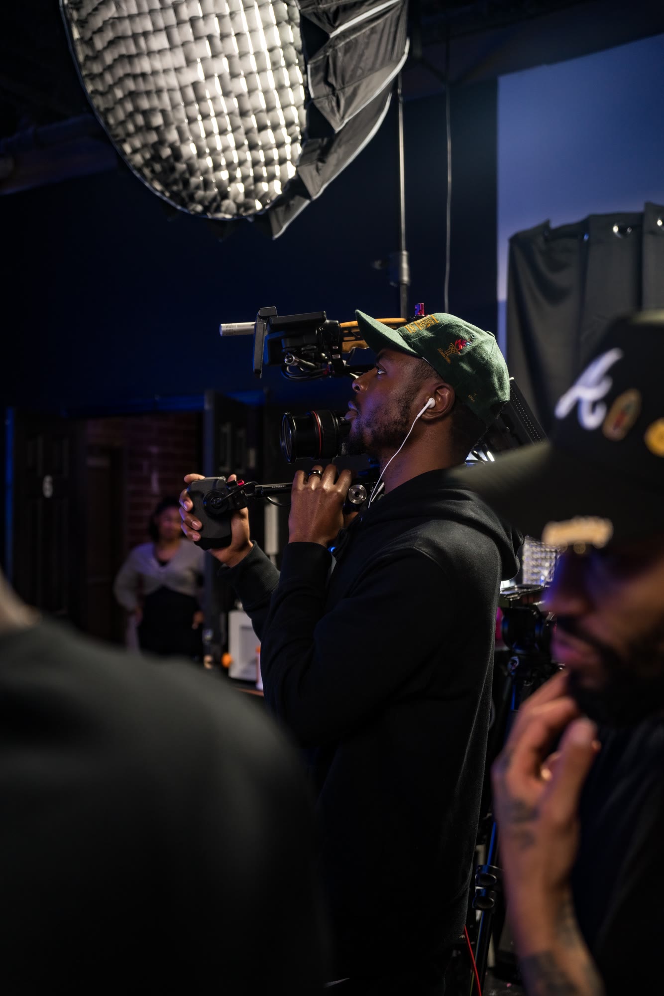 Tondric operating a camera with the crew on a studio set